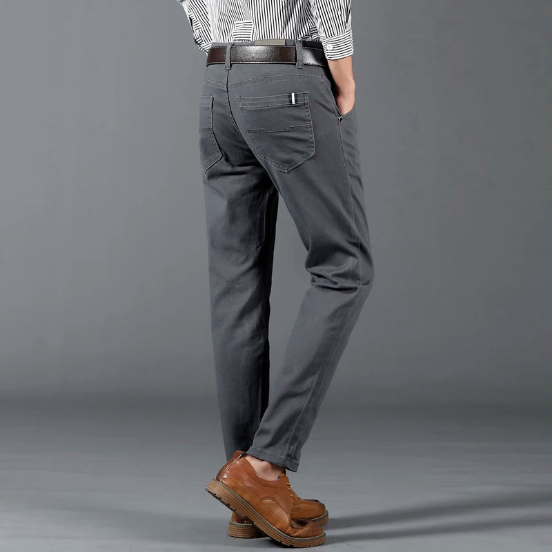Men's slim-fit gray cotton dress pants with back pockets, worn with brown leather shoes and striped shirt.