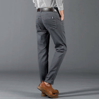 Men's slim-fit gray cotton dress pants with back pockets, worn with brown leather shoes and striped shirt.