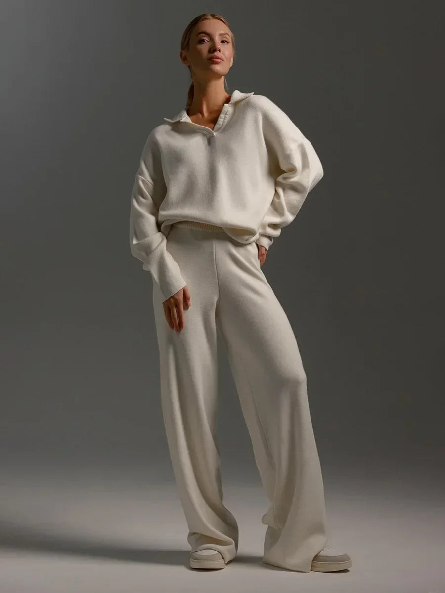 Woman wearing cream collared knit sweatshirt and matching wide-leg pants set with white platform sneakers.