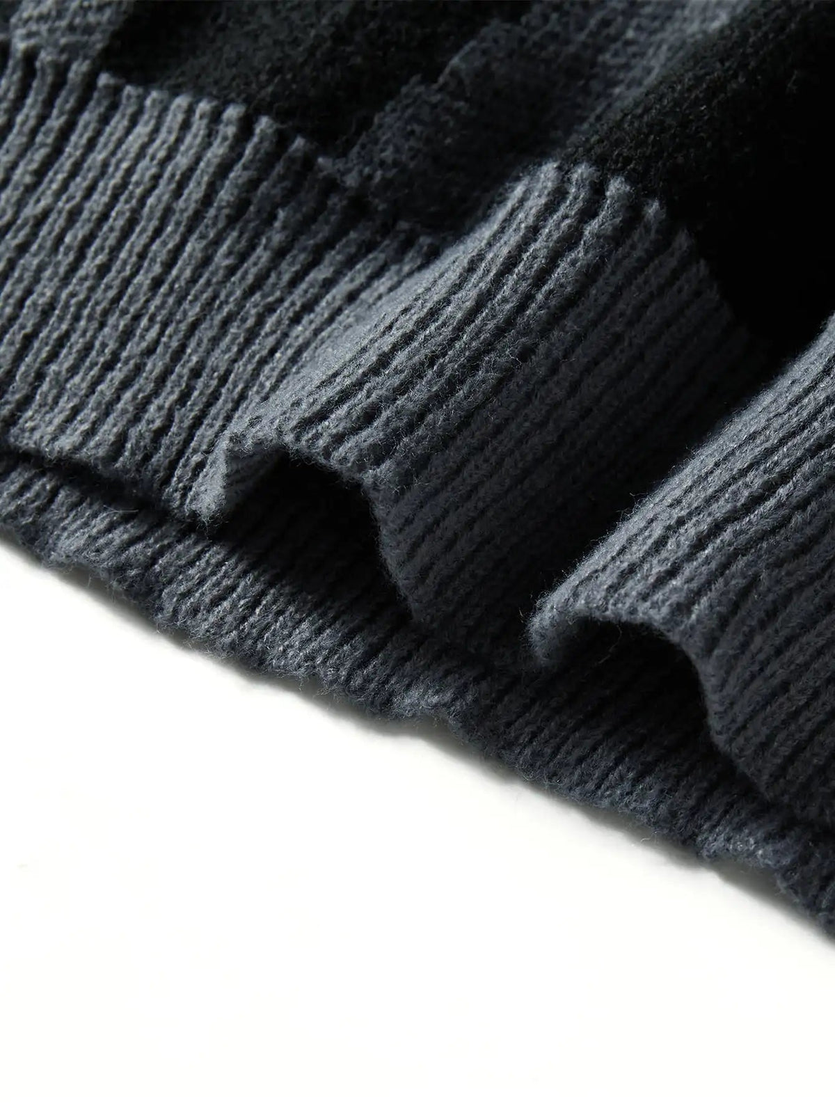 Close-up of dark grey wool knit oversized men's sweater showing ribbed hem detail and abstract texture pattern