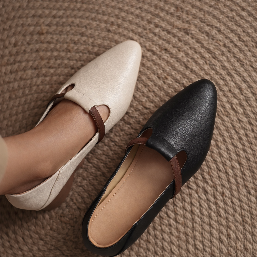 Women's pointed-toe T-strap flats in beige and black leather with brown strap detail, shown on woven rug background.