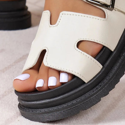Women's cream vegan leather platform sandals with adjustable buckle strap and chunky black sole, white pedicure visible