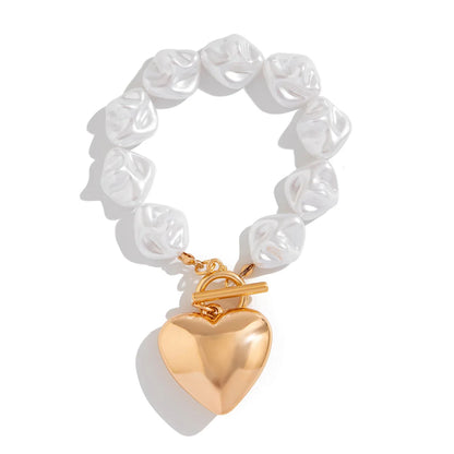 White baroque pearl bracelet with gold toggle clasp and large puffy heart charm pendant on white background