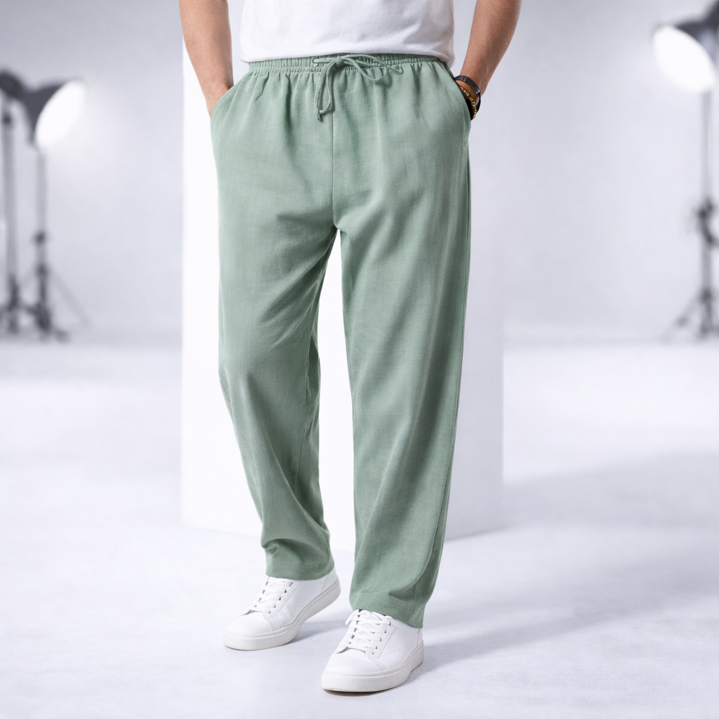 Man wearing sage green cotton drawstring pants with side pockets, paired with white sneakers and t-shirt.