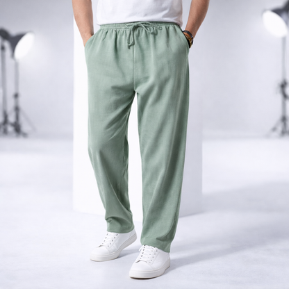 Man wearing sage green cotton drawstring pants with side pockets, paired with white sneakers and t-shirt.