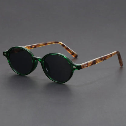 Round green frame sunglasses with tortoiseshell temples and dark lenses on gray background
