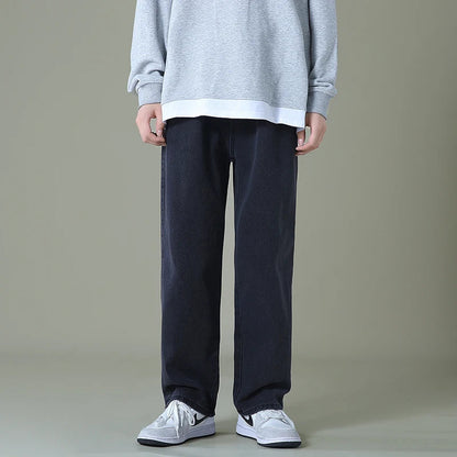 Man wearing relaxed-fit dark navy straight-leg denim jeans with gray sweatshirt and white Nike sneakers