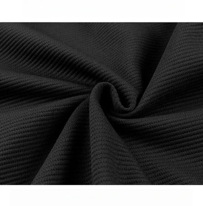 Close-up of black textured ribbed fabric with subtle waffle knit pattern, draped in soft folds showing fabric quality.
