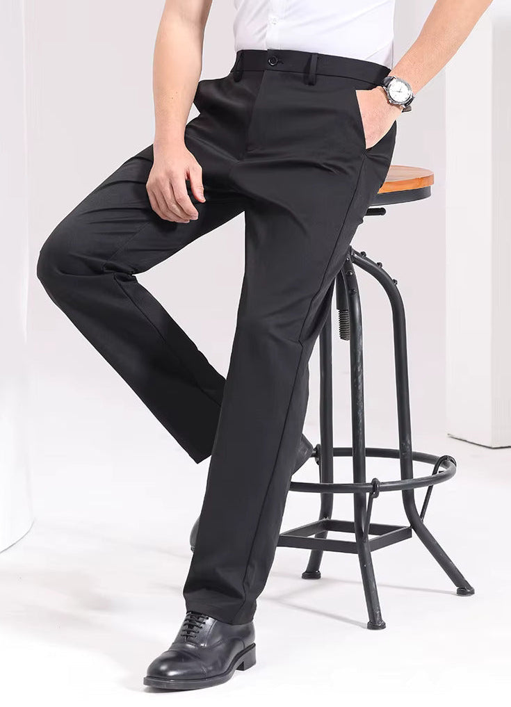 Man wearing black Viero slim-fit cotton dress trousers with white shirt and black oxford shoes, seated on bar stool.