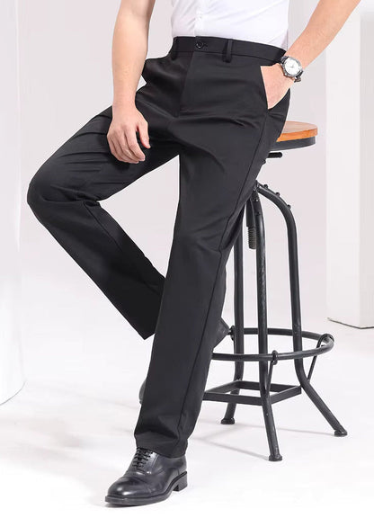 Man wearing black Viero slim-fit cotton dress trousers with white shirt and black oxford shoes, seated on bar stool.