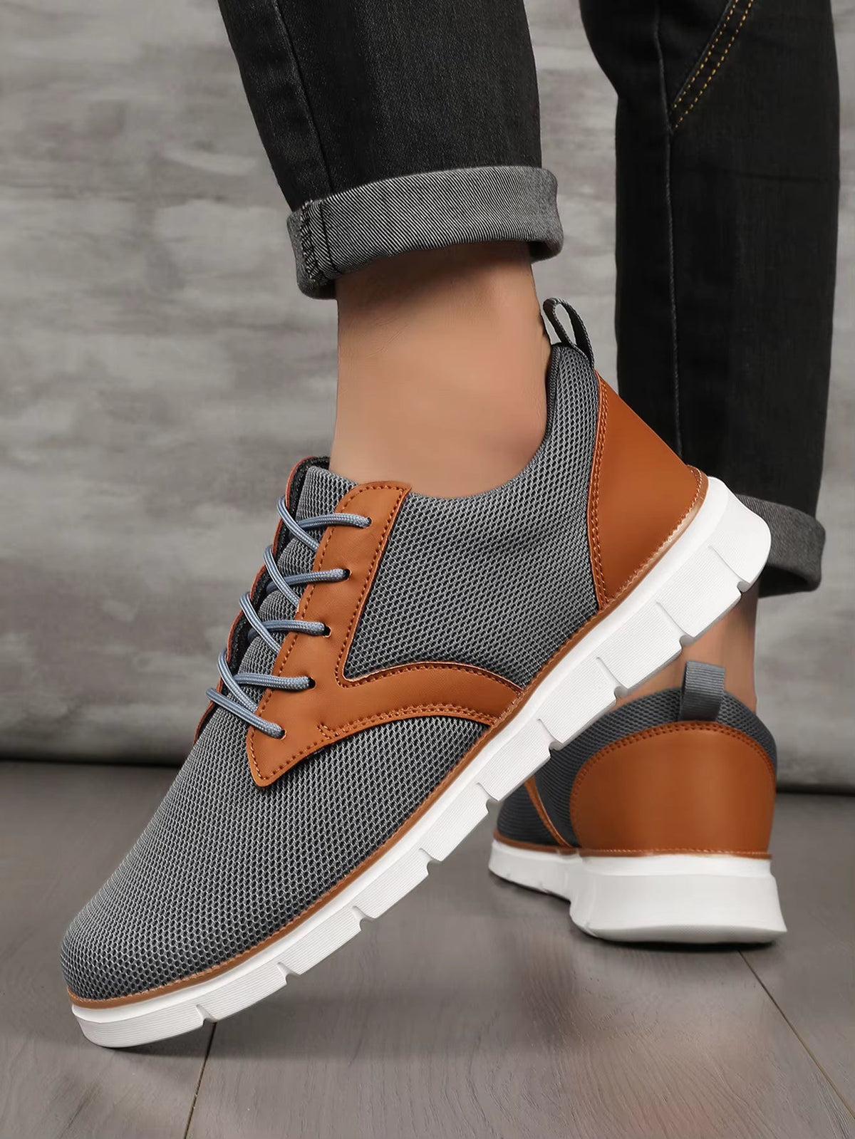 Gray and brown two-tone canvas leather lace-up orthopedic sneakers with white sole, shown on model wearing dark jeans.
