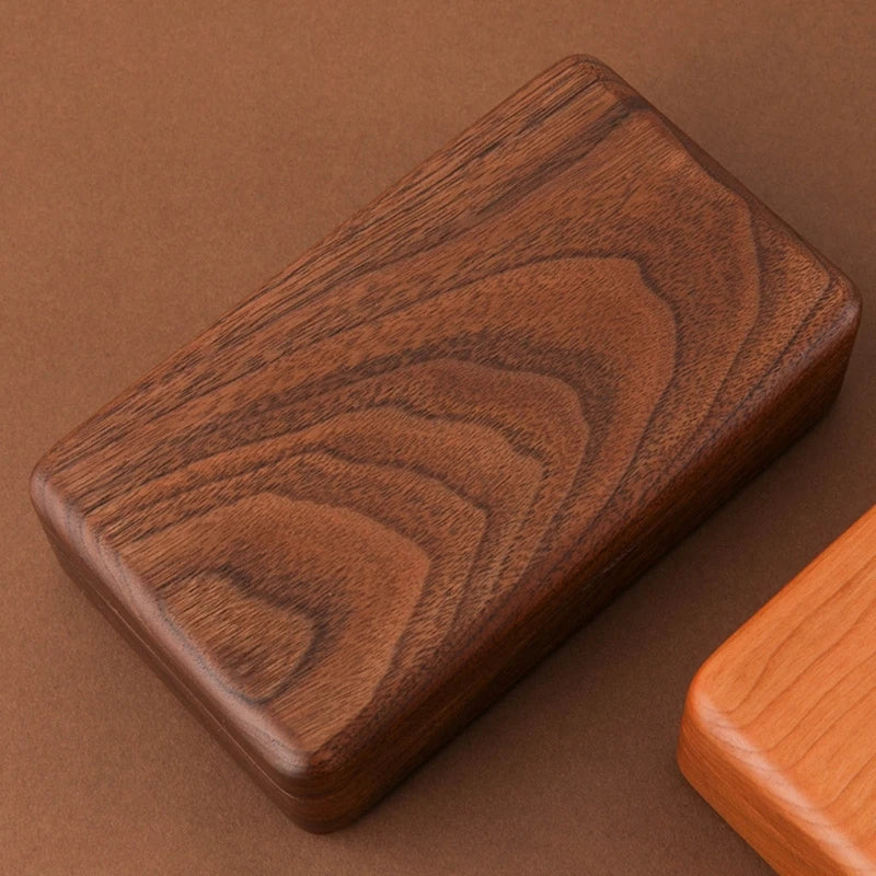 Dark walnut wooden jewelry box organizer with rich swirling grain pattern and rounded edges on brown background