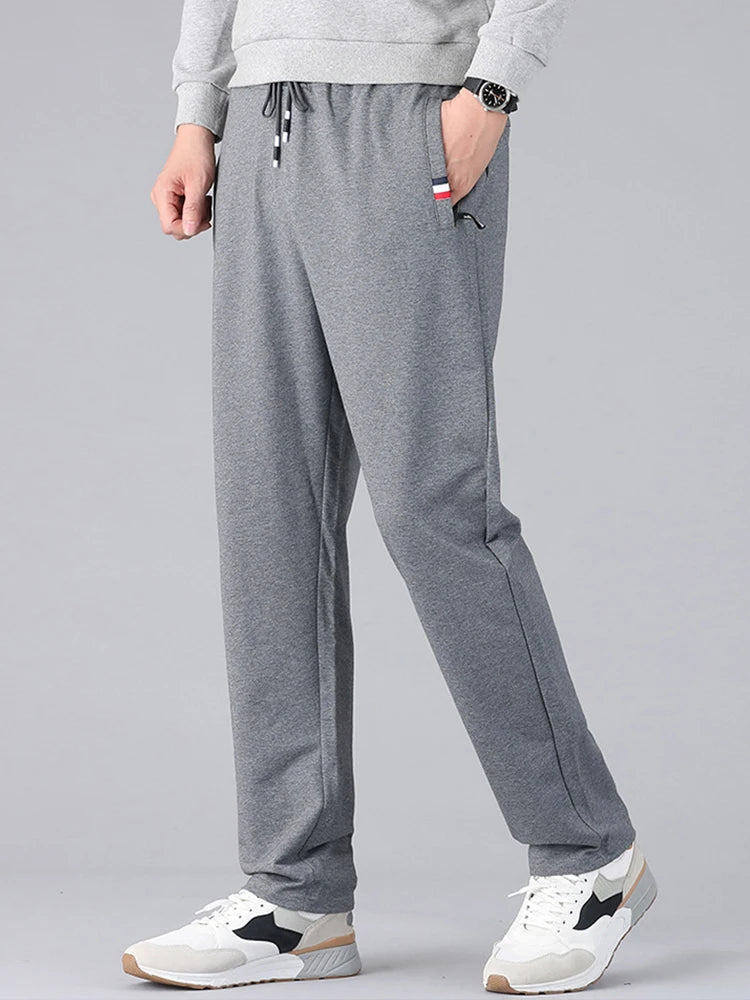 Men's gray cotton drawstring sweatpants with pockets, casual athletic joggers worn with white sneakers