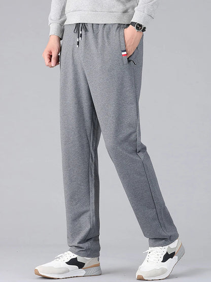 Men's gray cotton drawstring sweatpants with pockets, casual athletic joggers worn with white sneakers