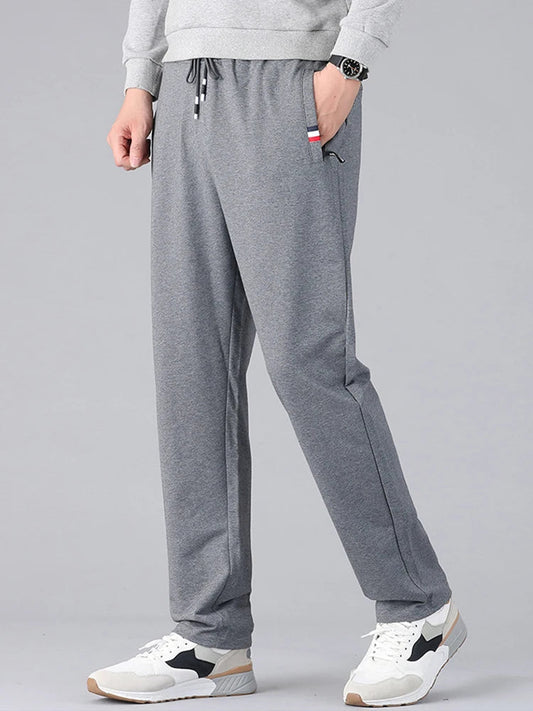 Men's gray cotton drawstring sweatpants with pockets, casual athletic joggers worn with white sneakers