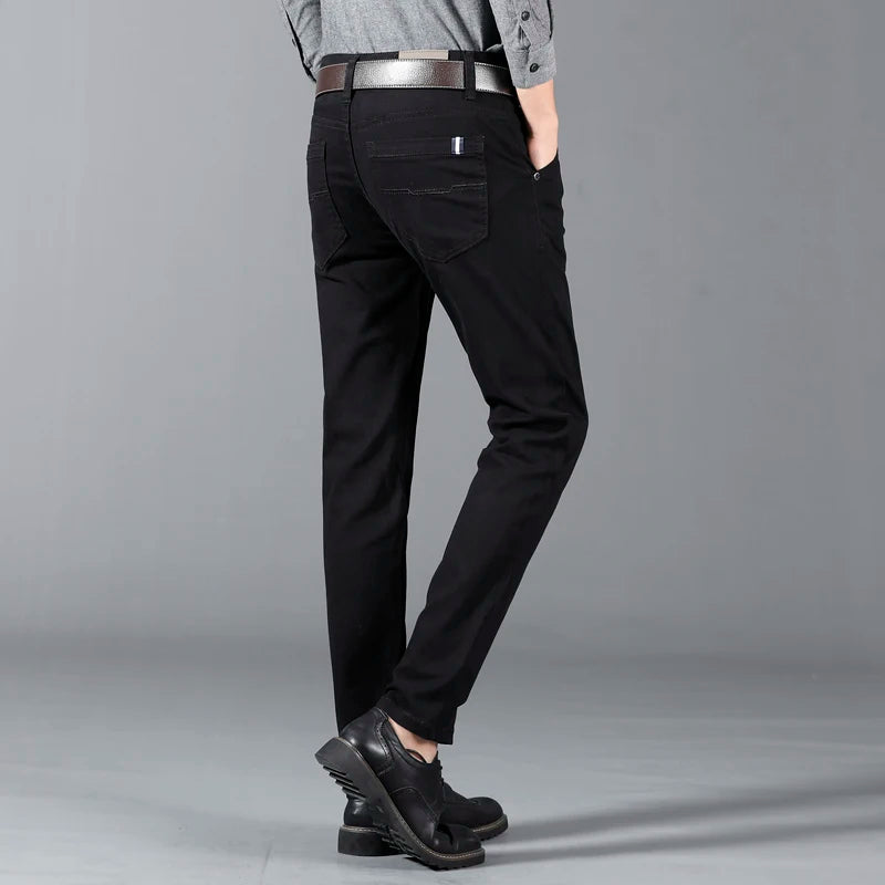 Man wearing slim-fit black cotton dress pants with leather belt and black dress shoes, rear view.