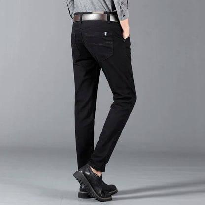 Man wearing slim-fit black cotton dress pants with leather belt and black dress shoes, rear view.