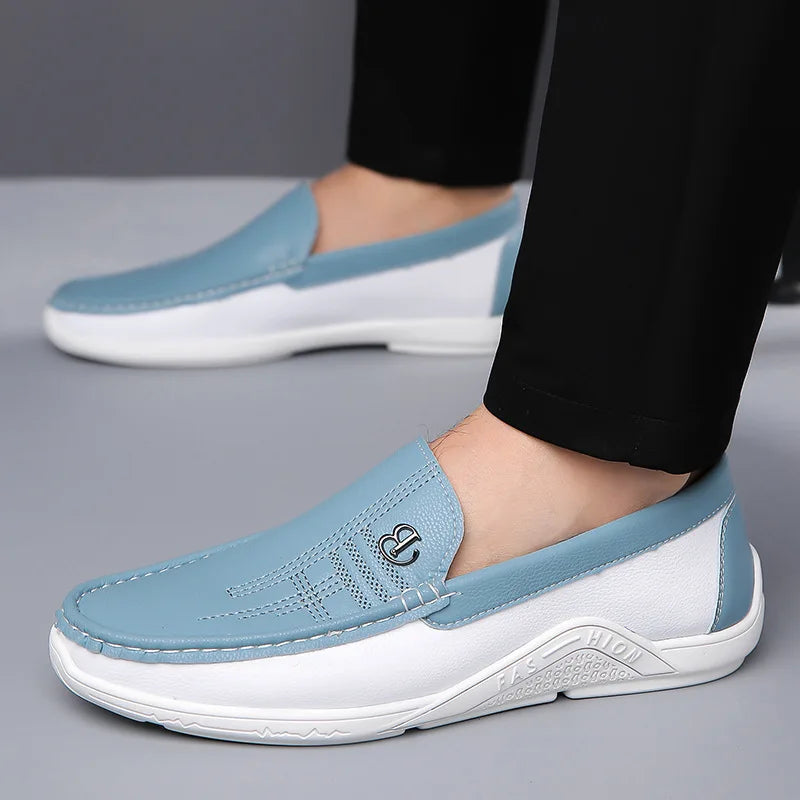 Light blue leather slip-on loafers for men with white sole, decorative stitching, and metal emblem detail.