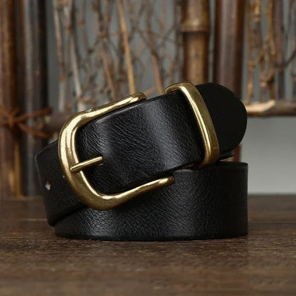 Black leather men's belt coiled on wood surface, featuring an antique brass pin buckle, rustic background