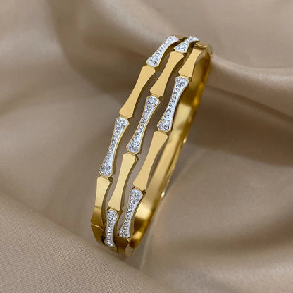 Geometric gold tone bangle bracelet with crystal stone accents and alternating polished segments for women
