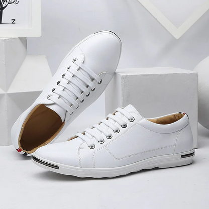 White leather low-top lace-up sneakers for men with tan interior and metal heel detail on geometric background