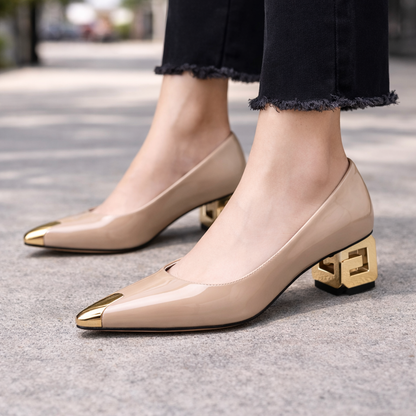 Nude patent leather block heel pumps with gold toe cap and decorative geometric heel, worn with black frayed jeans.