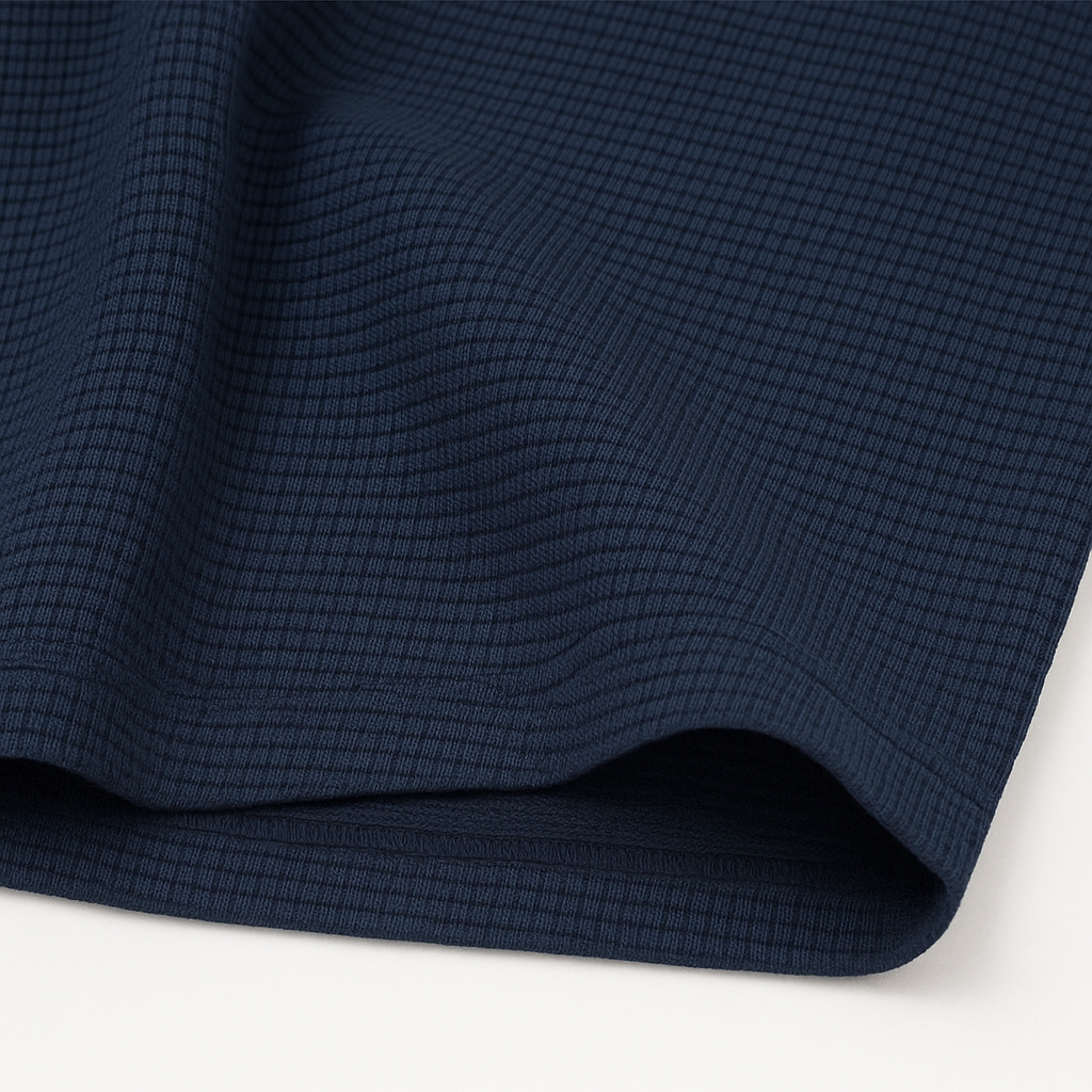 Navy blue waffle knit crewneck t-shirt fabric close-up showing textured grid pattern and soft drape.