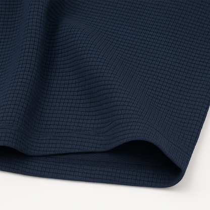 Navy blue waffle knit crewneck t-shirt fabric close-up showing textured grid pattern and soft drape.