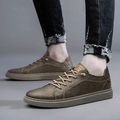 Men's olive green leather low-top lace-up sneakers with tan laces worn with distressed dark jeans