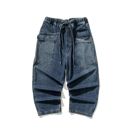 Men's wide-leg blue denim jeans with elastic drawstring waist, large cargo pockets, and relaxed fit silhouette