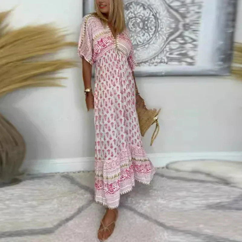 Woman wearing a pink and white bohemian printed short sleeve maxi dress with lace trim hem and V-neckline.