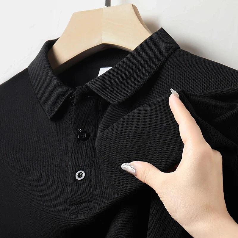 Black men's cotton polo shirt on hanger, close-up showing collar and button placket, hand touching fabric texture.