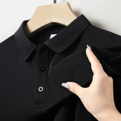 Black men's cotton polo shirt on hanger, close-up showing collar and button placket, hand touching fabric texture.