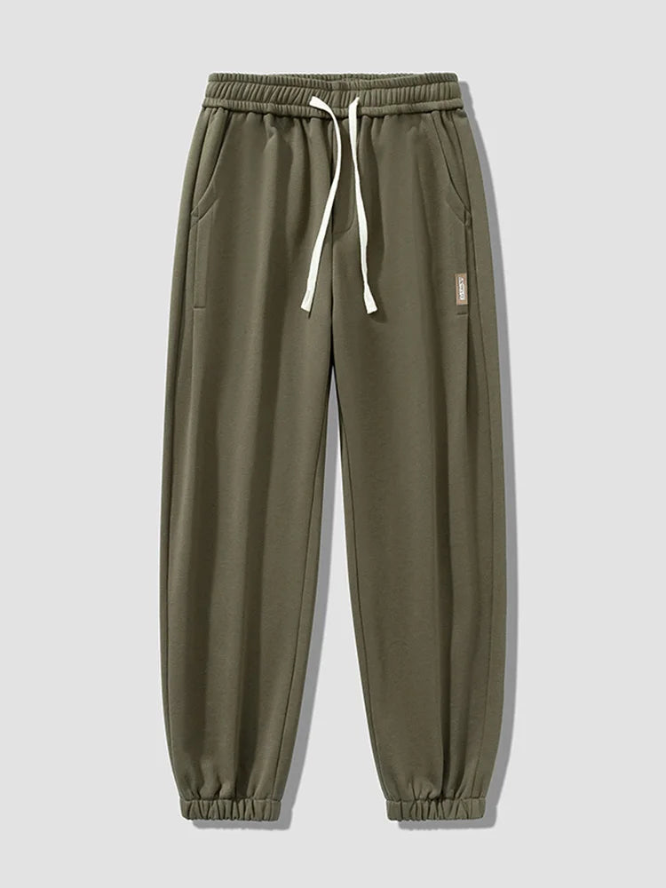 Army green men's relaxed fit cotton joggers with white drawstring waist and elastic cuffs, small label detail