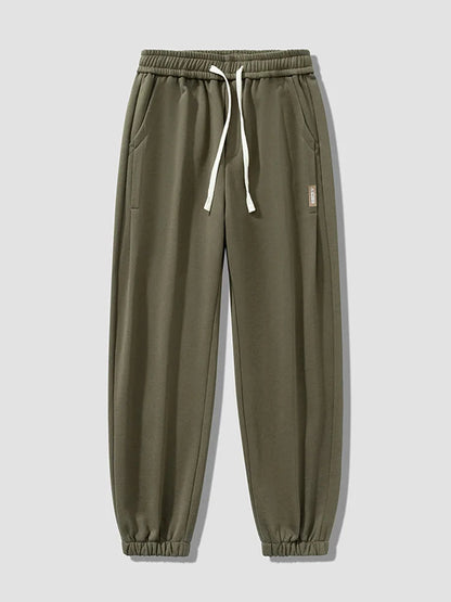 Army green men's relaxed fit cotton joggers with white drawstring waist and elastic cuffs, small label detail