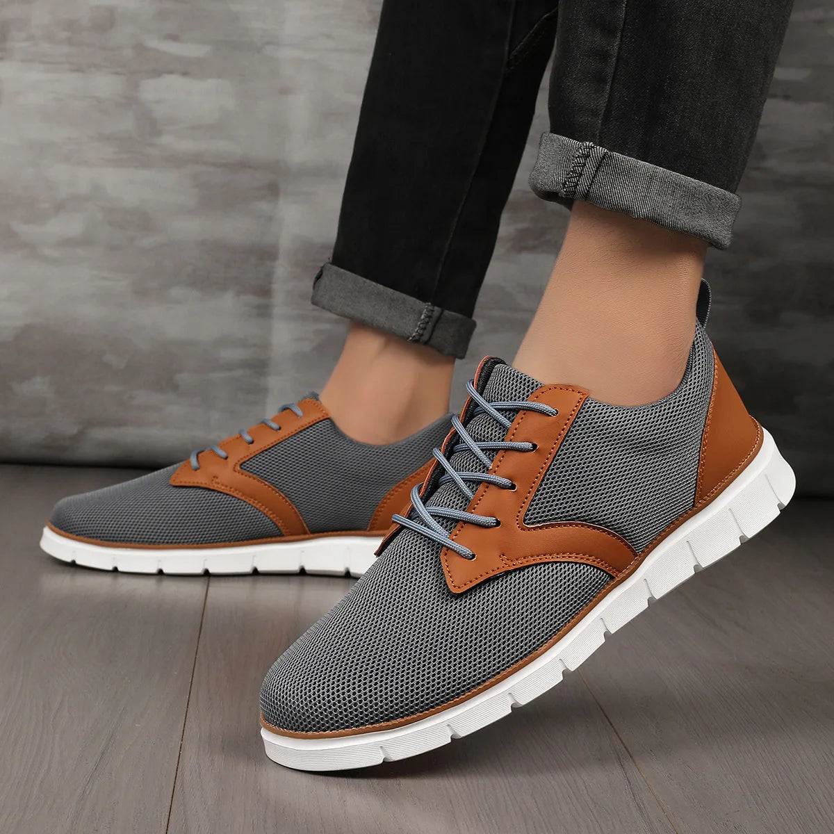 Gray and brown lace-up canvas leather orthopedic sneakers with white sole, worn with rolled dark jeans.
