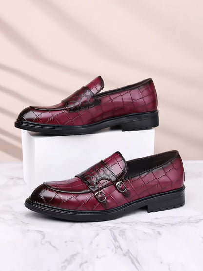 Burgundy croc-embossed men's double monk strap loafers with black sole displayed on white block and marble surface.