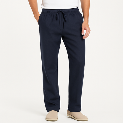 Men's navy blue cotton drawstring pants with elastic waistband, straight leg fit, worn with white tee and beige slip-on shoes.