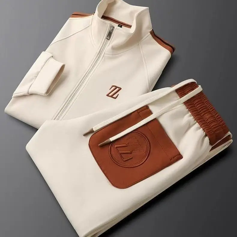 Cream men's zip-up tracksuit set with brown leather trim, embroidered logo, stand collar jacket and matching jogger pants.