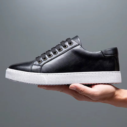 Black leather lace-up men's sneaker with white platform sole, held up against gray background, showcasing clean minimalist design.