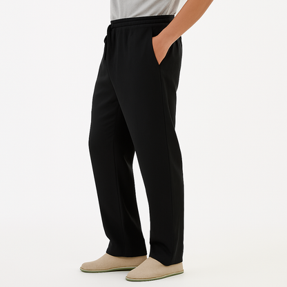 Man wearing black cotton drawstring pants with side pockets, paired with a gray tee and beige slip-on shoes.
