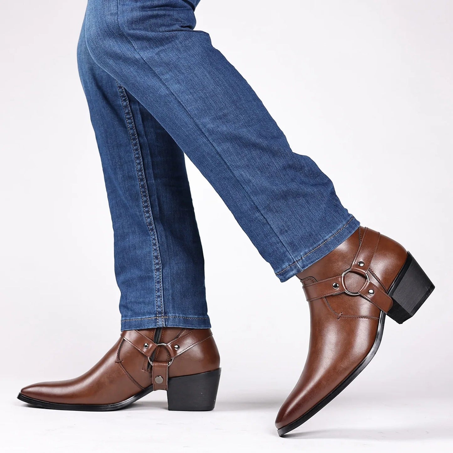 Men's brown leather harness ankle boots with block heel worn with blue jeans on white background