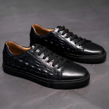 Black men's leather lace-up sneakers with crocodile embossed detail and tan interior lining on gray background