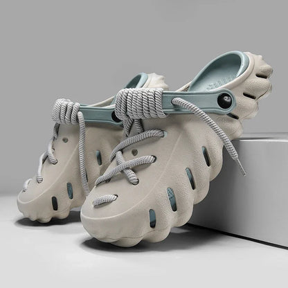 Beige foam clog shoes with gray rope laces and teal heel strap, featuring ventilation holes and cushioned sole