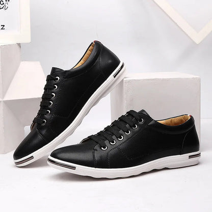 Black leather low-top lace-up sneakers for men with white sole, metallic eyelets, and smooth upper on white display blocks