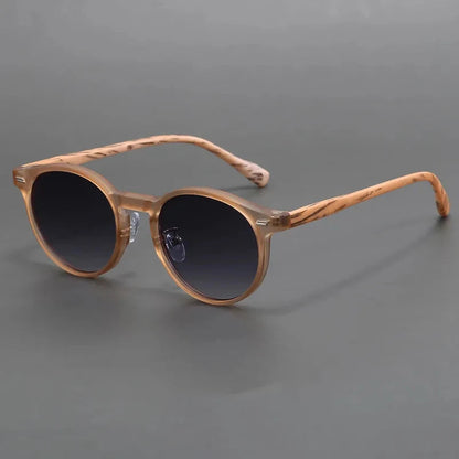 Round sunglasses with wood-grain tan acetate frames and gradient dark gray lenses on gray background