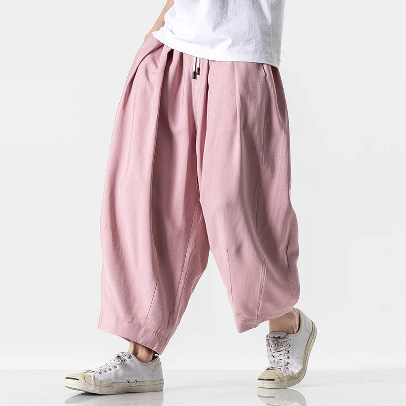 Men's wide-leg pink cotton drawstring harem pants paired with white sneakers and a white t-shirt, casual streetwear style.