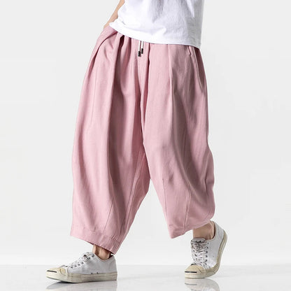 Men's wide-leg pink cotton drawstring harem pants paired with white sneakers and a white t-shirt, casual streetwear style.