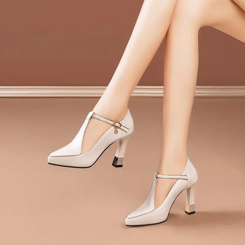 White women's T-strap block heel pumps with gold buckle accent and pointed toe, shown on model's feet.