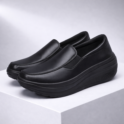 Black women's slip-on platform sneakers with smooth faux leather upper, elastic side panels, and chunky rocker sole.